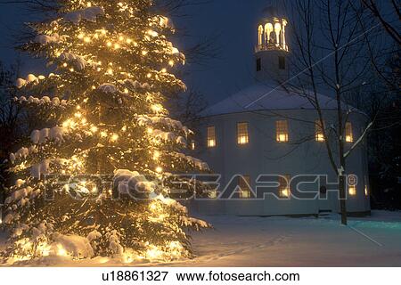 Stock Photo -  Christmas tree, church, chapel, decorations, holiday, town, outdoor, winter, snow, Vermont, A large evergreen tree with bright white lights and candles in the windows of the Old Round Church (a 16-sided polygon) National Historical Landmark are decorated. Fotosearch