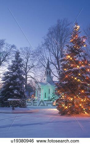 Stock Photograph -  Christmas tree, winter scene, church, chapel, outdoor, natural, evening, decorations, Christmas tree, holiday, town, village, snow, Vermont, Scenic view of The First Baptist Church of Bristol and a large evergreen tree on the Green decorated with colorfu. Fotosearch