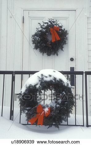 Stock Photo -  Christmas wreath, wreaths, decoration, ribbon, Christmas, holiday, snow, winter, Two snow covered green wreaths with red bows decorate the outside of a the Union Church for Christmas in Plymouth Notch in Windsor County in the state of Vermont. . Fotosearch