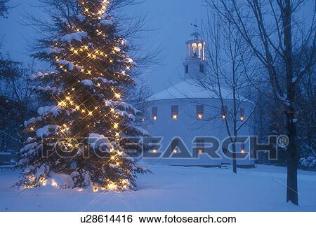 Stock Photograph -  church, Christmas tree, chapel, winter, decorations, outdoor, natural, town, holiday, snow, Vermont, A large evergreen tree with white lights and candles in the windows of the Old Round Church (a 16-sided polygon) National Historical Landmark are decorat. Fotosearch