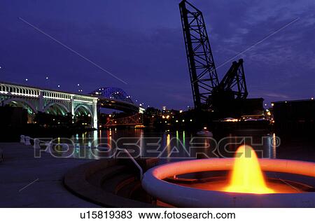 Stock Image -  Cleveland, fountain, OH, Ohio, Flats District, Fountain at Settlers Landing Park along the Cuyahoga River in the Flats District of downtown Cleveland illuminated at night.. Fotosearch