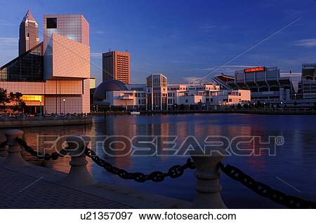 Stock Photo -  Cleveland, skyline, hall of fame, rock 'n roll, OH, Ohio, Skyline of downtown Cleveland and the Rock and Roll Hall of Fame and Museum along the waterfront of North Coast Harbor at sunset.. Fotosearch
