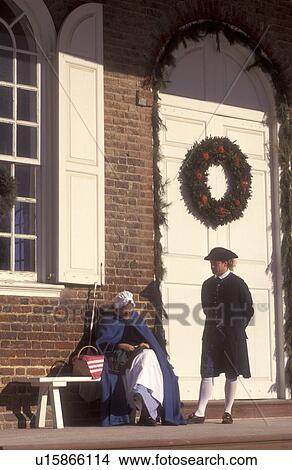 Picture -  Colonial Williamsburg, Virginia, VA, Williamsburg, Interpreters dressed in colonial costumes talk outside the Courthouse which is decorated with a Christmas wreath in Colonial Williamsburg.. Fotosearch