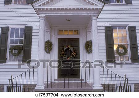 Picture -  Colonial Williamsburg, Virginia, VA, Williamsburg, A colonial house is decorated with wreaths for Christmas in Colonial Williamsburg in the evening.. Fotosearch