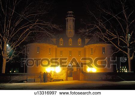 Stock Photo -  Colonial Williamsburg, Virginia, VA, Williamsburg, Illumination of Palace Green at Christmas in the evening in Colonial Williamsburg. Flickering cresset lights guide visitors through tours of historic buildings.. Fotosearch