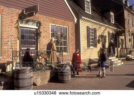 Stock Photo -  Colonial Williamsburg, Virginia, VA, Williamsburg, Interpreters wearing colonial costumes stand outside the village stores in Colonial Williamsburg.. Fotosearch