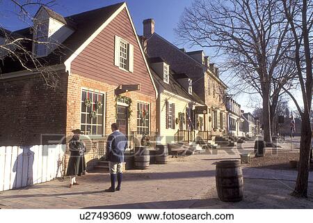 Stock Photo -  Colonial Williamsburg, Virginia, VA, Williamsburg, Interpreters wearing colonial costumes stand outside a village store in Colonial Williamsburg.. Fotosearch