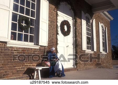 Colonial Williamsburg, Virginia, VA, Williamsburg, A woman interpreter dressed in a colonial costume sits outside the Courthouse which is decorated with a Christmas wreath in Colonial Williamsburg. View Large Photo Image Stock Photography - Colonial Williamsburg, Virginia, VA, Williamsburg, A woman interpreter dressed in a colonial costume sits outside the Courthouse which is decorated with a Christmas wreath in Colonial Williamsburg.. Fotosearch