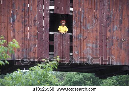 Stock Photo -  covered bridge, spring, Northfield Falls, VT, Vermont, Woman stands in window of Slaughter House Covered Bridge in the spring in Northfield Falls.. Fotosearch