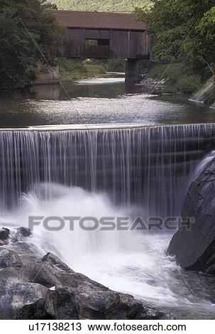 Stock Image -  covered bridge, waterfall, Vermont, VT, The Warren Covered Bridge ca. 1880 crosses over the Mad River as it cascades over the waterfall in Warren. . Fotosearch