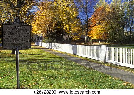 Stock Photo -  Deerfield, Massachusetts, MA, The Berkshires, White fence along the sidewalk and Old Deerfield sign in Historic Deerfield in the autumn.. Fotosearch