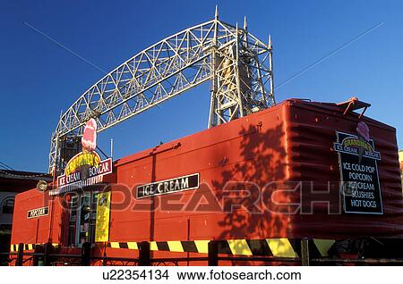 Picture -  Duluth, MN, Minnesota, Aerial Lift Bridge, 386 feet long, towers over the Ice Cream Box Car at Canal Park in Duluth in the evening.. Fotosearch