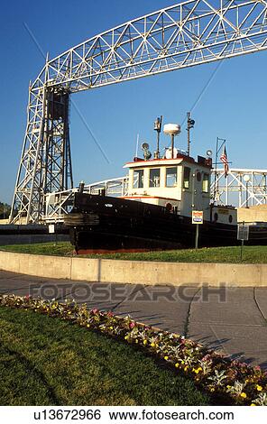Duluth, MN, Minnesota, Aerial Lift Bridge, 386 feet long, towers above a tugboat displayed at Canal Park in Duluth. View Large Photo Image Stock Photograph - Duluth, MN, Minnesota, Aerial Lift Bridge, 386 feet long, towers above a tugboat displayed at Canal Park in Duluth.. Fotosearch