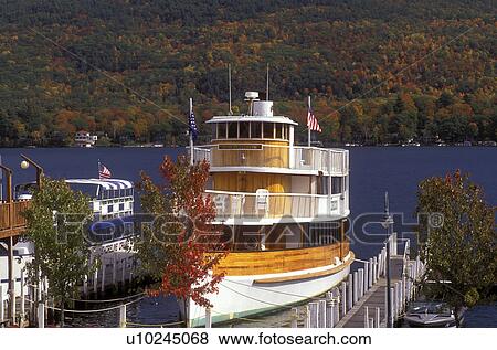 Stock Photo -  excursion, Lake George, New York, NY, Adirondacks, Wooden tour boat from Shoreline Cruises moored on a dock on Lake George in the autumn.. Fotosearch