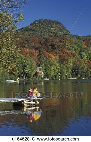 fall, lake, Westmore, VT, Vermont, Mother and daughter sitting together back-to-back on a dock on Long Pond in the autumn. Daughter is reading a book. View Large Photo Image Stock Photo - fall, lake, Westmore, VT, Vermont, Mother and daughter sitting together back-to-back on a dock on Long Pond in the autumn. Daughter is reading a book.. Fotosearch