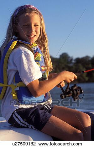 Stock Image -  fishing, lake, MN, Minnesota, Alexandria, 8 year old Young girl wearing a life jacket fishes from a boat on Maple Lake in Alexandria. . Fotosearch