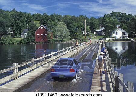 Stock Photo -  floating bridge, Vermont, VT, Car crosses over the floating bridge on Sunset Lake in Brookfield. People swimming and fishing off the bridge.. Fotosearch