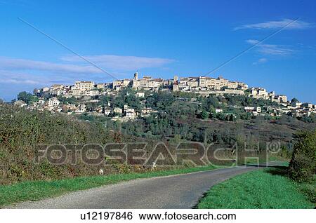Stock Photograph -  France, Midi-Pyrenees, the Dordogne, Quercy, Cordes-sur-Ciel, Tarn, Europe, A narrow road winds up to the scenic medieval hilltop village of Cordes-sur-Ciel.. Fotosearch