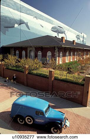 Stock Photo -  Georgia, GA, Atlanta, Blue antique car in front of Georgia Whaling Wall at Underground Atlanta over Georgia Railroad Depot.. Fotosearch
