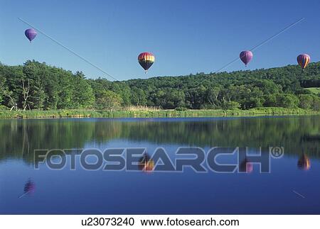 Stock Image -  hot air balloon, Vermont, VT, Quechee, Hot air balloons fly above the water at the Quechee Hot Air Balloon Festival.. Fotosearch