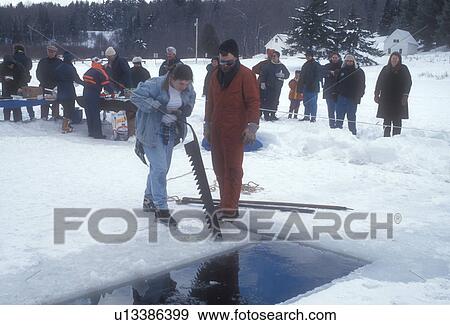 Stock Photo -  ice harvest, frozen lake, winter, Brookfield, VT, Vermont, People gather around to watch the ice cutting contest at the Ice Harvest Festival on the frozen Sunset Lake in Brookfield in winter.. Fotosearch