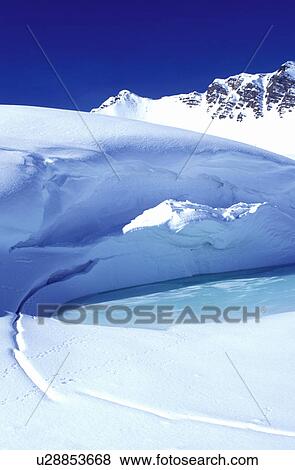 Stock Photo -  ice, snow, Alps, Switzerland, Valais, Les Crosets, Portes du Soleil, Swiss Alps, Europe, Turquoise colored ice forms on a pond high in the Swiss Alps in the winter.. Fotosearch