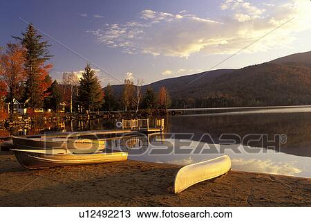 Stock Image -  lake, Adirondacks, New York, Blue Mountain Lake, NY, A canoe and two rowboats on the beach on Blue Mountain Lake in the fall in the Adirondacks.. Fotosearch