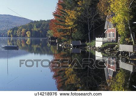 Stock Photograph -  lake, reflection, fall, Barnet, VT, Vermont, Reflection of boats and summer cottages in the calm waters of Harveys Lake in the autumn.. Fotosearch