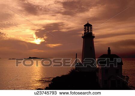 Stock Image -  lighthouse, sunrise, sunset, Newfoundland, NF, Canada, A lighthouse at sunrise in Ship Cove over the Atlantic Ocean.. Fotosearch