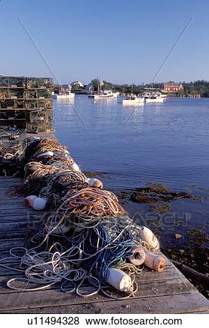 Stock Photo -  Maine, ME, Corea, Lobster traps and fishing nets on a dock in the scenic harbor of the fishing village of Corea.. Fotosearch