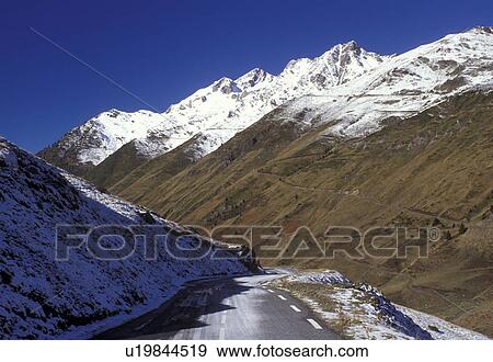 Stock Photo -  Midi-Pyrenees, The Pyrenees, France, Col du Tourmalet, Hautes-Pyrenees, Europe, A mountain road winds down through the snow capped Pyrenees Mountains and the valley below of Col du Tourmalet.. Fotosearch
