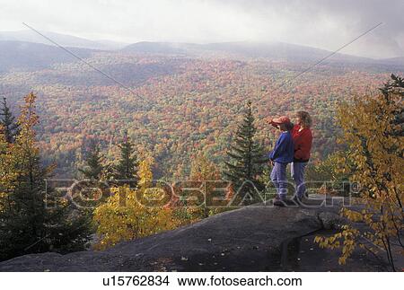 Picture -  mother and daughter, fall, overlook, aerial, hiking, Groton State Forest, VT, Vermont, Mother and daughter look out over the colorful fall foliage of the forest from Owl's Head Overlook in Groton State Forest in the autumn.. Fotosearch
