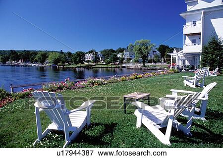 Stock Photo -  New Hampshire, Meredith, NH, inn, resort, lodge, hotel, Adirondack chairs on the waterfront of Lake Winnipesaukee at The Inn at Mill Falls.. Fotosearch