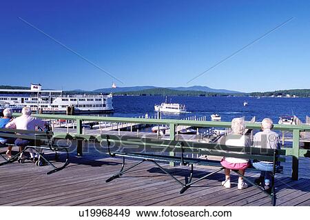 New Hampshire, Weirs Beach, NH, People sitting on benches on the boardwalk at Weirs Beach watching the M. S. Mt. Washington Cruise Boat on Lake Winnipesaukee. View Large Photo Image Stock Photo - New Hampshire, Weirs Beach, NH, People sitting on benches on the boardwalk at Weirs Beach watching the M. S. Mt. Washington Cruise Boat on Lake Winnipesaukee.. Fotosearch