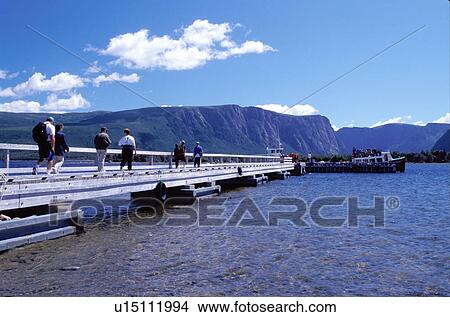 Picture -  Newfoundland, NF, Canada, People walking on the pier towards the tour boat on Western Brook Pond in Gros Morne National Park. . Fotosearch