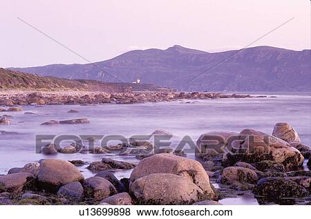 Stock Photo -  Newfoundland, NF, Canada, Rocky coast on the Gulf of St. Lawrence at low tide in the morning. Gros Morne National Park. Lobster Cover Head Lighthouse.. Fotosearch