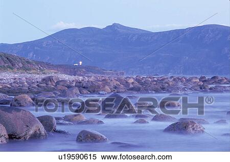 Stock Photography -  Newfoundland, NF, Canada, Rocky coast on the Gulf of St. Lawrence at low tide in the morning. Gros Morne National Park. Lobster Cover Head Lighthouse.. Fotosearch
