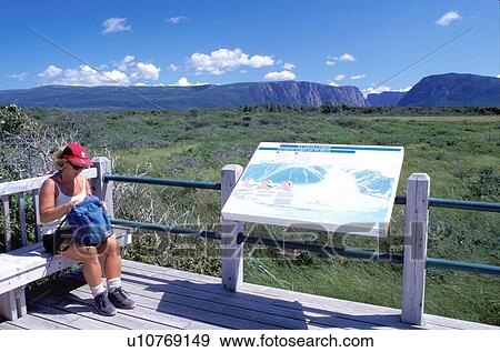 Stock Photo -  Newfoundland, NF, Canada, Woman taking a break at an overlook at Western Brook Pond in Gros Morne National Park. . Fotosearch