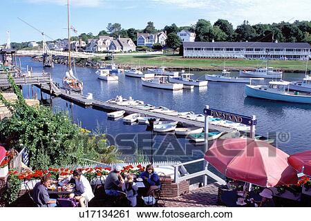 Stock Image -  outdoor cafT, Perkins Cove, Ogunquit, Maine, ME, People sitting on the terrace at Barnacle Billy's on the scenic fishing harbor in the village of Perkins Cove on the Atlantic Ocean. . Fotosearch