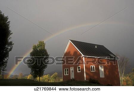 Picture -  rainbow, Waterbury, VT, Vermont, A colorful rainbow appears over a small red house after a storm. . Fotosearch
