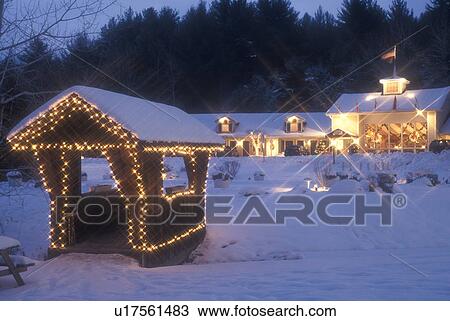 Stock Image -  resort, inn, Stowe, holiday, ski resort, covered bridge, snow, evening, decorations, Christmas, winter, Vermont, The small covered bridge at The Mountain Road Resort in Stowe is decorated for the Christmas holiday season on a snow covered evening in Lamo. Fotosearch