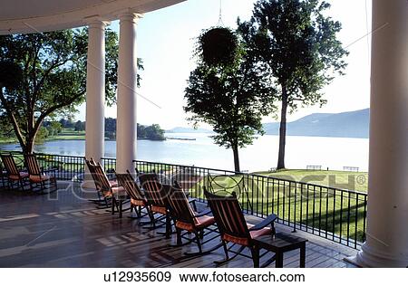 Stock Photo -  resort, rocking chairs, Cooperstown, New York, Rocking chairs on the porch of The Otesaga Resort Hotel and golf course in Cooperstown, NY.. Fotosearch