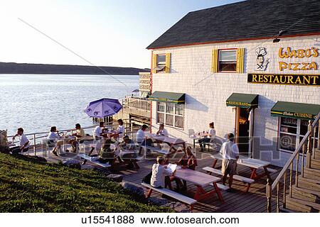restaurant, Cape Breton, Nova Scotia, NS, Canada, People sitting on the deck of Wabu's Pizza in the village of Cheticamp on the waterfront of the Gulf of St. Lawrence in Cape Breton.  View Large Photo Image Stock Photo -  restaurant, Cape Breton, Nova Scotia, NS, Canada, People sitting on the deck of Wabu's Pizza in the village of Cheticamp on the waterfront of the Gulf of St. Lawrence in Cape Breton. . Fotosearch