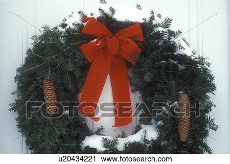 ribbon, red bow, wreaths, Christmas wreath, decoration, close-up, Christmas, holiday, snow, winter, A snow covered green wreath with a red bow and two pine cones decorate the outside door of a house in the state of Vermont. View Large Photo Image Stock Image - ribbon, red bow, wreaths, Christmas wreath, decoration, close-up, Christmas, holiday, snow, winter, A snow covered green wreath with a red bow and two pine cones decorate the outside door of a house in the state of Vermont. . Fotosearch