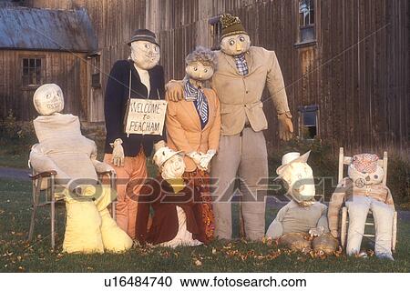 Stock Image -  scarecrow, fall decoration, display, decorations, autumn, A fall decoration of a family of scarecrows in front of a barn with a Welcome to Peacham sign in Peacham in Caledonia County in the state of Vermont.. Fotosearch
