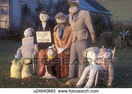 Stock Image -  scarecrow, fall decorations, display, decoration, autumn, A fall decoration of a family of scarecrows on a lawn with a Welcome to Peacham sign in Peacham in Caledonia County in the state of Vermont.. Fotosearch