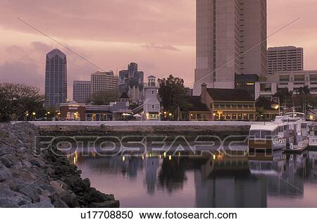 Stock Image -  shopping center, San Diego, California, CA, Seaport Village a modern shopping and dining complex on San Diego Bay and the downtown skyline of San Diego in the evening.. Fotosearch