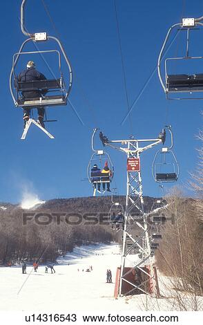 Stock Image -  skiing, ski lift, winter, Warren, VT, Vermont, Skiers riding on chair lift at Sugarbush Ski Resort in Warren in winter.. Fotosearch