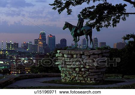 Stock Image -  skyline, Kansas City, MO, Missouri, A bronze statue of Indian Scout overlooks the downtown skyline of Kansas City from Penn Valley Park in the evening.. Fotosearch