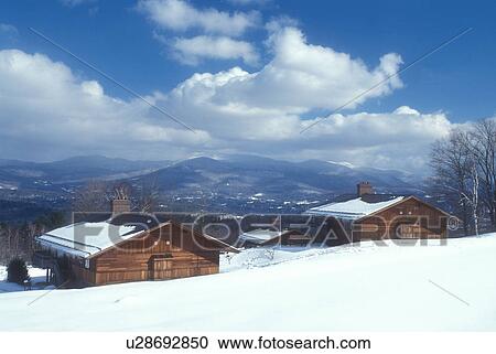 Stock Image -  snow-covered chalets, Trapp Family Lodge, lodging, TFL, Stowe, Vermont, VT, Guest houses at the Trapp Family Lodge overlook the scenic mountains in Stowe in the winter.. Fotosearch